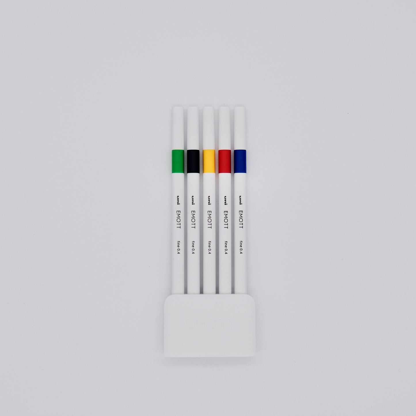 Set of white pens with colored bands in a holder on a light gray background