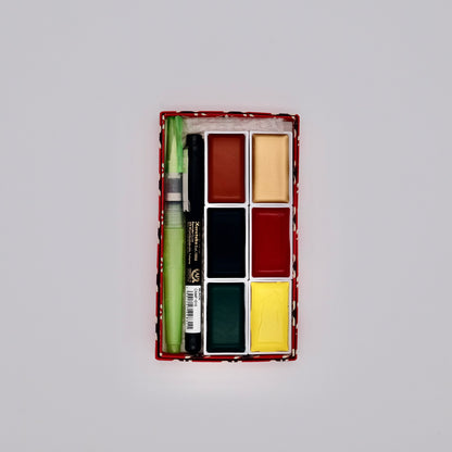 Set of watercolor paints with a brush in a rectangular box on a light gray background