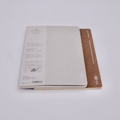 Two notebooks, one open with text and the other closed with a brown cover, on a white background.