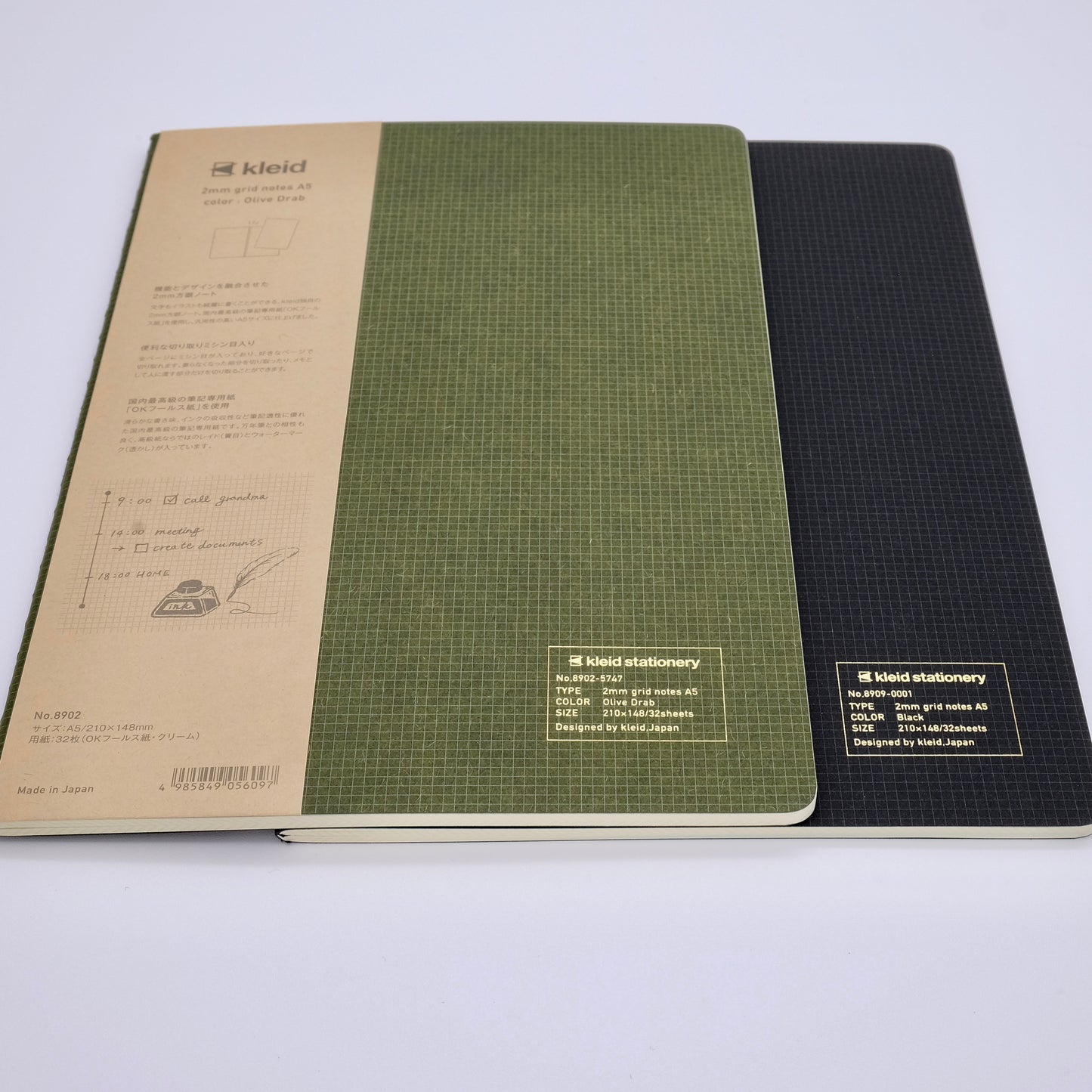 Two notebooks, one green and one black, with visible branding on a white background