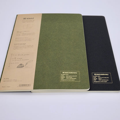 Two notebooks, one green and one black, with visible branding on a white background