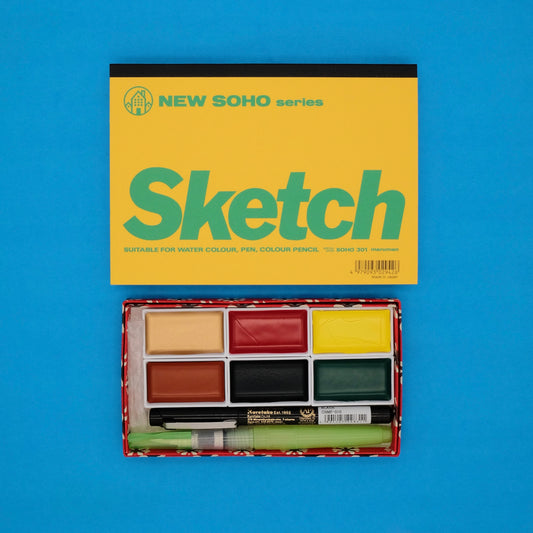 Sketchbook set with watercolor paints and markers on a blue background