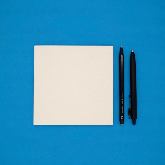 White notebook and two black pens on a blue background