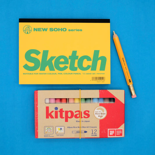 Sketchbook and Kitpas crayon set on a blue background