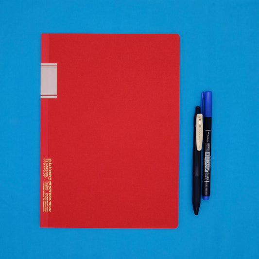 Red notebook with three pens on a blue background