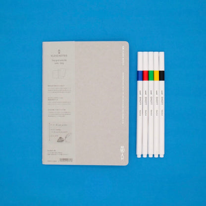Notebook and colored markers on a blue background