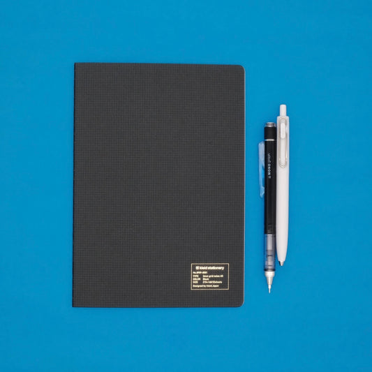 Black notebook with two pens on a blue background