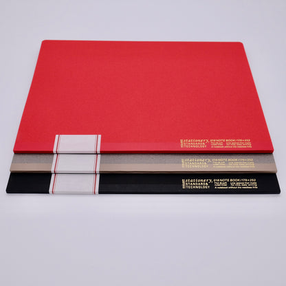 Three red, black, and gray notebooks stacked on a light gray background