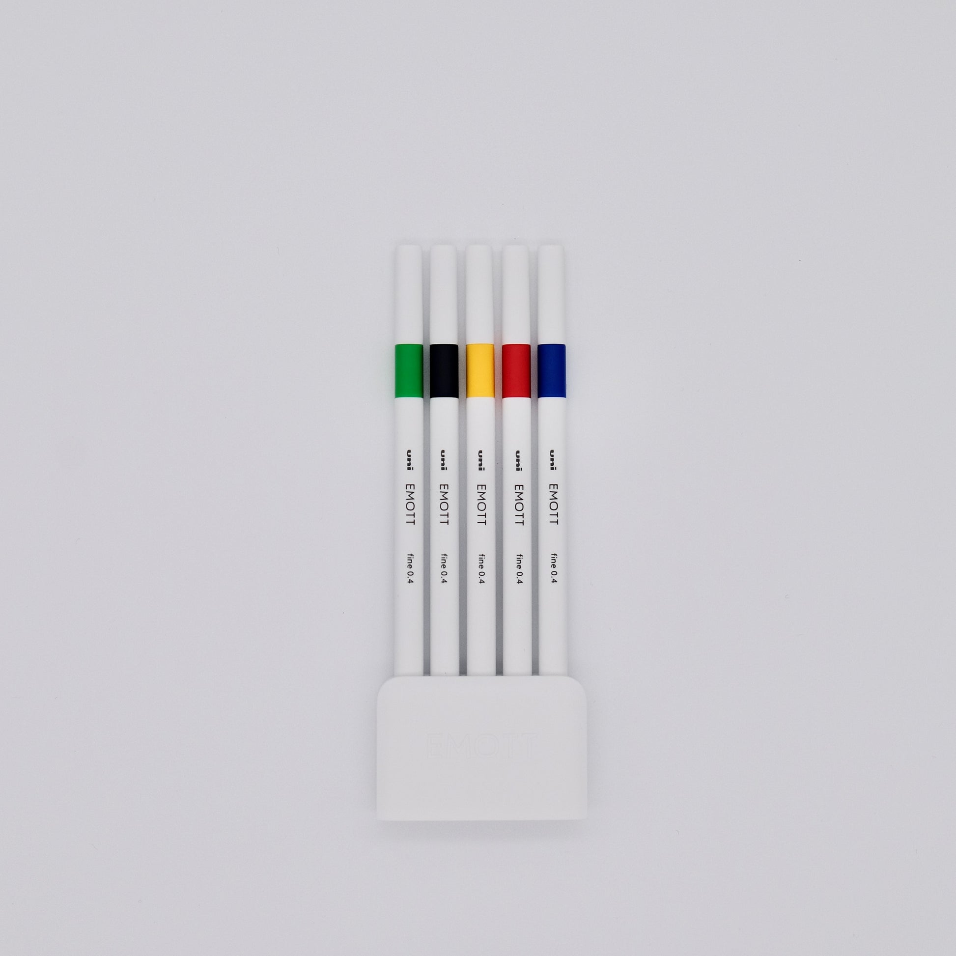 Set of white pens with colored bands in a holder on a light gray background